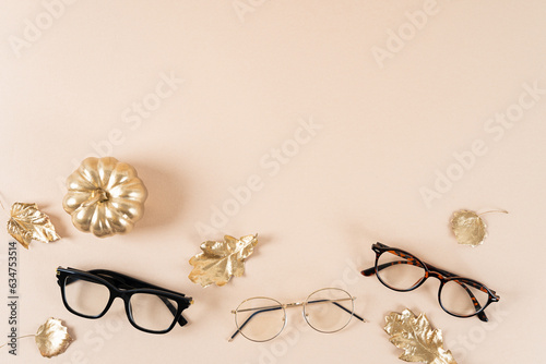 Eyewear and glasses sale concept. Trendy sunglasses on beige background with a pumpkin and golden leaves. Trendy Fashion fall accessories. Copy space for text. Autumn sale. Optic store discount poster