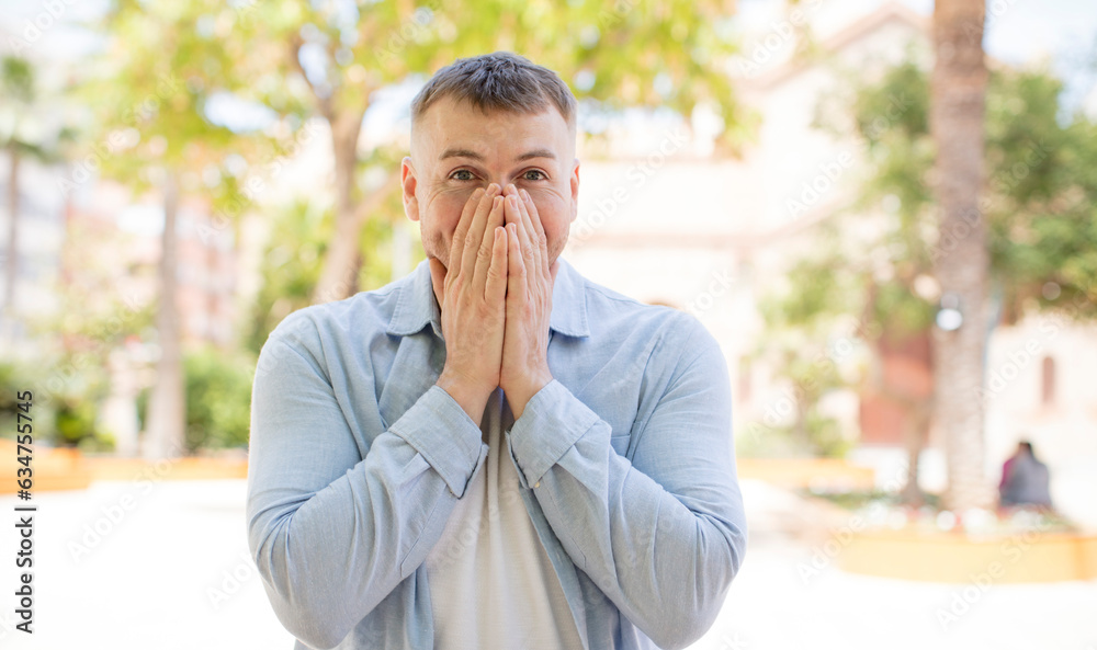 handsome man looking happy, cheerful, lucky and surprised covering mouth with both hands handsome man looking happy, cheerful, lucky and surprised covering mouth with both hands