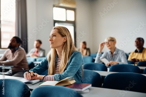 Photos Mid adult woman paying attention during class in lecture hall.