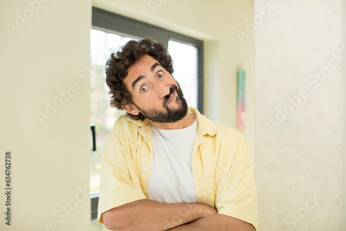 young crazy bearded man shrugging, feeling confused and uncertain, doubting with arms crossed and puzzled look