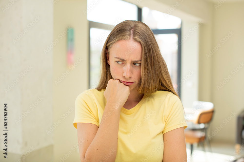 pretty blond woman feeling serious, thoughtful and concerned, staring sideways with hand pressed against chin pretty blond woman feeling serious, thoughtful and concerned, staring sideways with hand pressed against chin