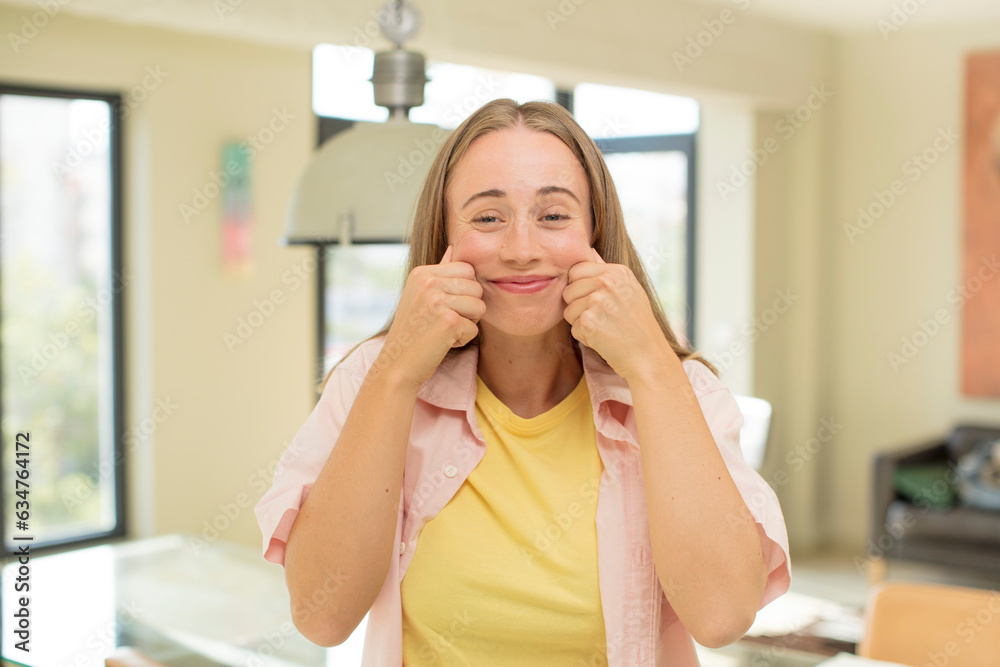 pretty blond woman smiling and pointing to own fake smile pretty blond woman smiling and pointing to own fake smile
