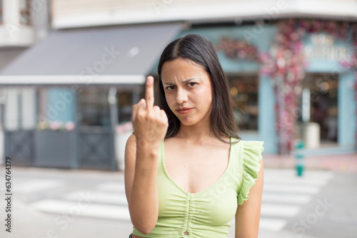 pretty hispanic woman feeling angry, annoyed, rebellious and aggressive, flipping the middle finger, fighting back