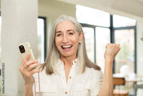pretty senior woman feeling shocked,laughing and celebrating success. smartphone concept
