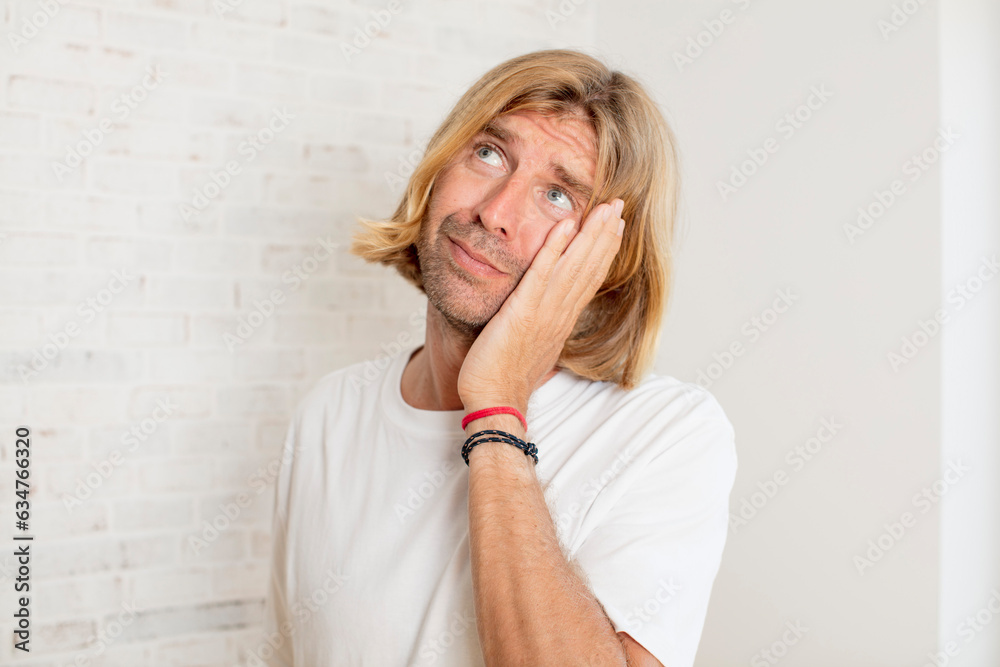 young blond adult man feeling bored, frustrated and sleepy after a tiresome, dull and tedious