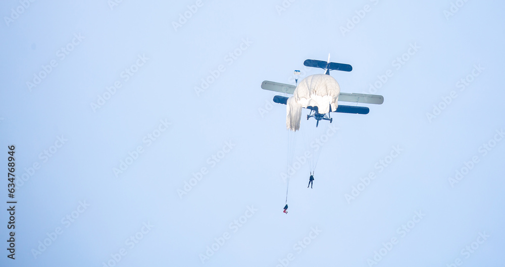 Fototapeta premium Skydiving. Parachutists jump from a flying plane in the air. Extreme sport and entertainment.