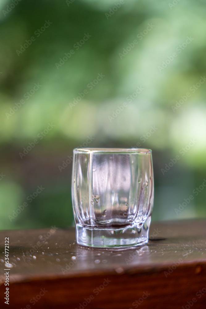 shot glass on a wooden table, with a green background shot glass on a wooden table, with a green background