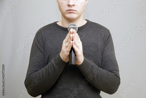 A young man holding a microphone with both hands.  photo