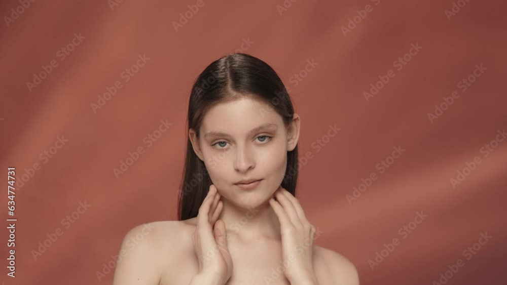 A young woman demonstrates perfect facial skin. Portrait of a smiling seminude woman in the studio on a red background close up. The concept of natural beauty, cosmetology, skin care. A young woman demonstrates perfect facial skin. Portrait of a smiling seminude woman in the studio on a red background close up. The concept of natural beauty, cosmetology, skin care.