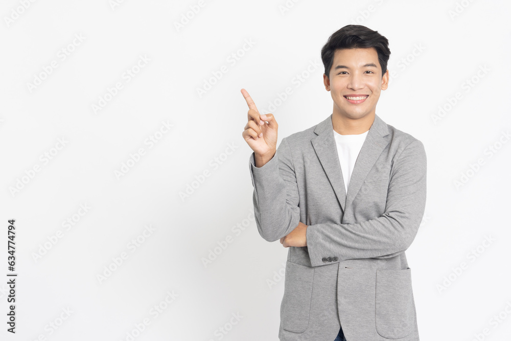 Young Asian businessman smiling and pointing to empty copy space isolated on white background Young Asian businessman smiling and pointing to empty copy space isolated on white background