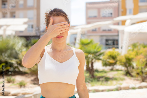 pretty young woman covering eyes with one hand feeling scared or anxious, wondering or blindly waiting for a surprise