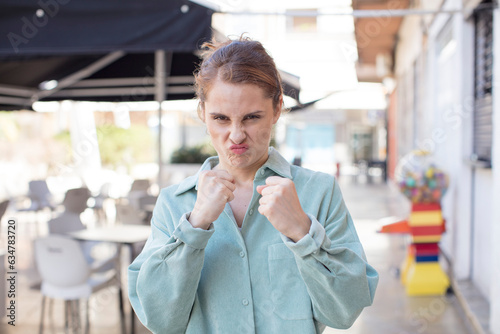 pretty young woman looking confident, angry, strong and aggressive, with fists ready to fight in boxing position