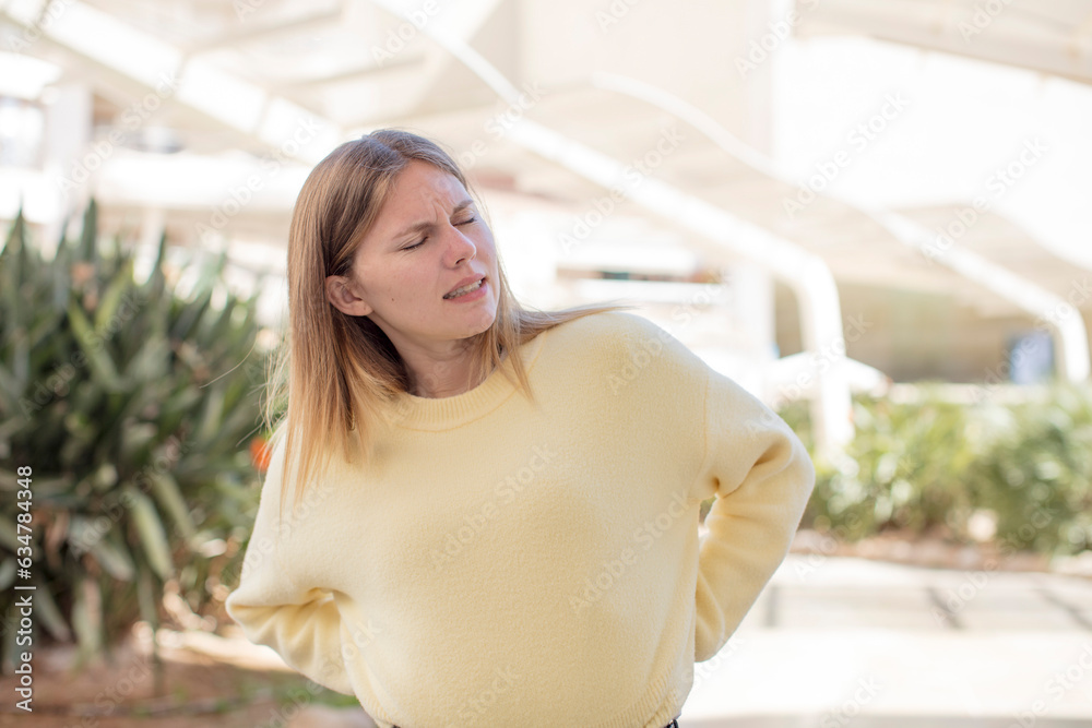 pretty young woman feeling anxious, ill, sick and unhappy, suffering a painful back ache pretty young woman feeling anxious, ill, sick and unhappy, suffering a painful back ache