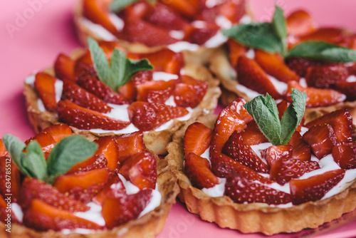 Fresh strawberry tarts closeup on plate. Tarts decorated with mint leaves.