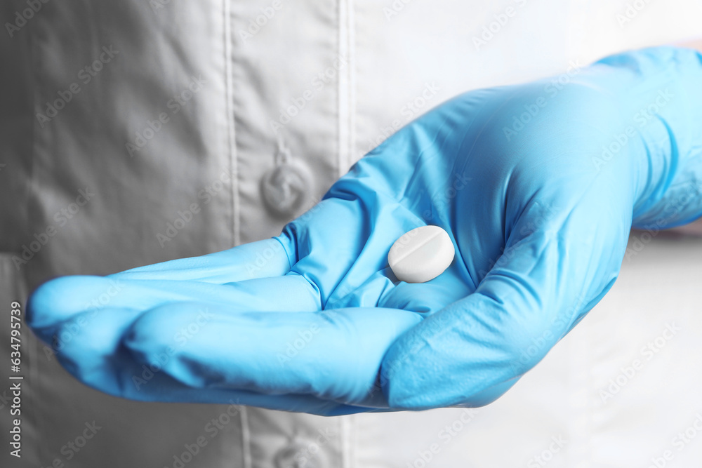Doctor in medical glove holding pill, closeup view Doctor in medical glove holding pill, closeup view