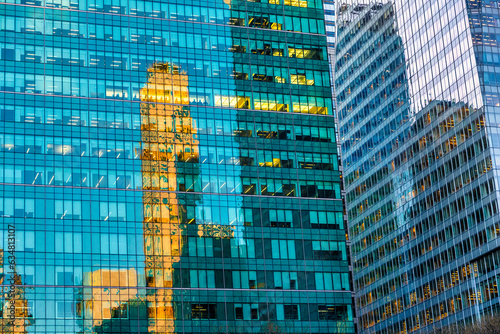 View of a contemporary glass Office skyscraper reflecting an orange old skysraper in Midtown Manhattan, Reflection in the sunlight. New York City, Skyscraper, Building Exterior, Office Building, USA photo
