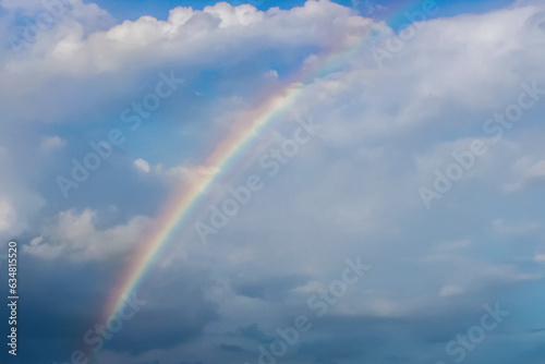 Beautiful rainbow in the blue sky, white clouds © Katerryna.R