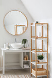 Interior of bathroom with sink bowl, bath accessories, mirror and shelving unit