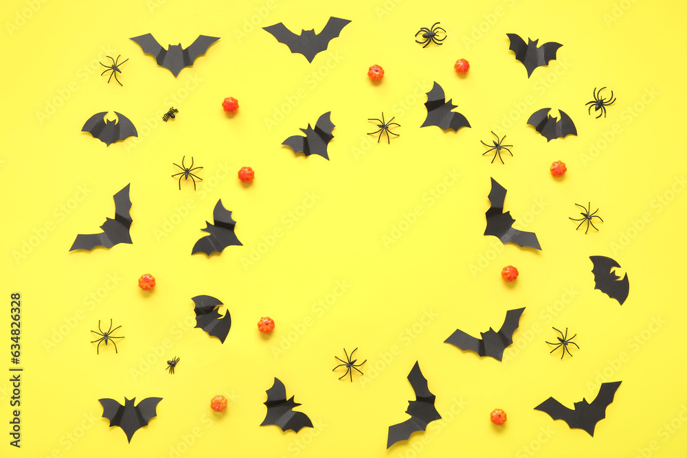 Frame made of pumpkins, paper bats and spiders on yellow background. Halloween celebration concept