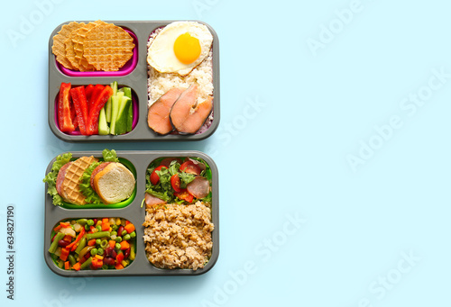 Lunchboxes with different delicious food on blue background