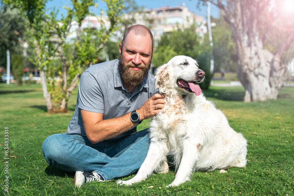 Portrait of Man pet owner with his happy pet dog golden retriever outside on lawn public park during summer. Portrait of Man pet owner with his happy pet dog golden retriever outside on lawn public park during summer.