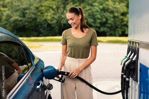 Foto Smiling Woman Refilling Auto with Fuel at Modern Petrol Station