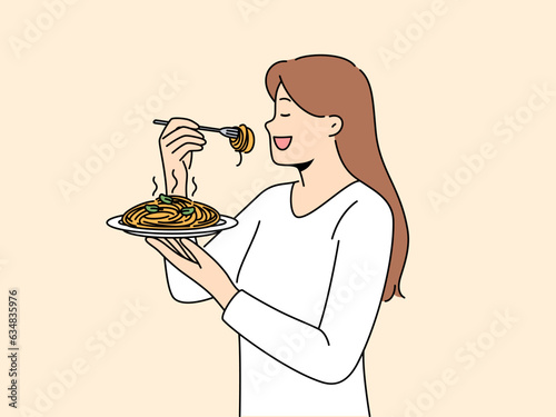 Woman stands with plate of spaghetti in hands and eats italian dish enjoying taste of pasta. Girl eats pasta to satisfy hunger and rejoice at opportunity to try delicious high-calorie food