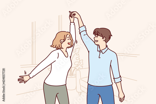 Cheerful couple dancing in apartment rejoicing moving and relocation to new house taken on mortgage in bank. Happy man and woman dancing waltz celebrating buying real estate in luxury area