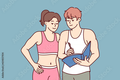 Man fitness trainer advises girl, drawing up training plan to achieve new sports heights. Woman athlete stands near fitness instructor helping to get rid of excess weight and get attractive figure