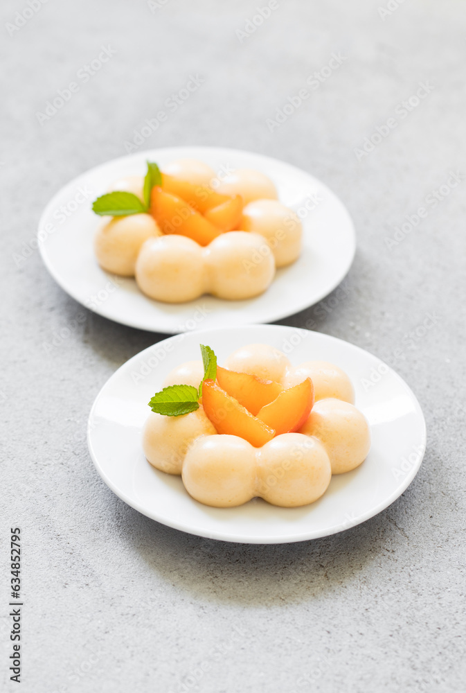 Apricot cream dessert, Panna Cotta in the shape of truffles, decorated with fresh apricot slices. On a plate. LIght grey background. Close up Apricot cream dessert, Panna Cotta in the shape of truffles, decorated with fresh apricot slices. On a plate. LIght grey background. Close up