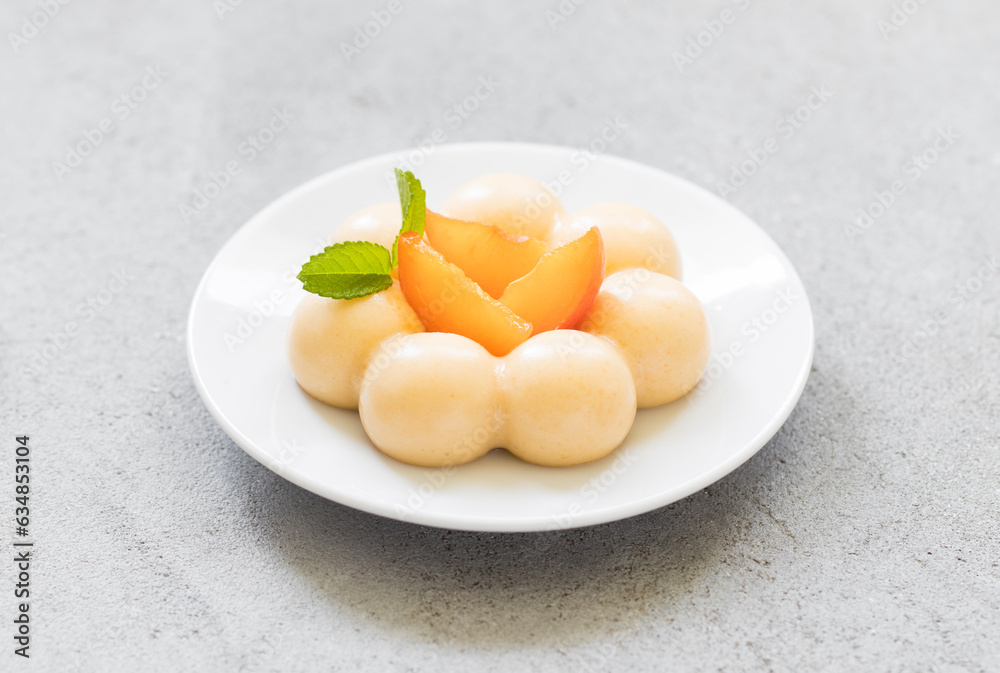 Apricot cream dessert, Panna Cotta in the shape of truffles, decorated with fresh apricot slices. On a plate. LIght grey background. Close up Apricot cream dessert, Panna Cotta in the shape of truffles, decorated with fresh apricot slices. On a plate. LIght grey background. Close up