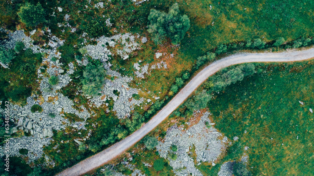 Aerial view of narrow road among green summer fields in the Italian Alps, high angle view. Natural texture for background. Aerial view of narrow road among green summer fields in the Italian Alps, high angle view. Natural texture for background.