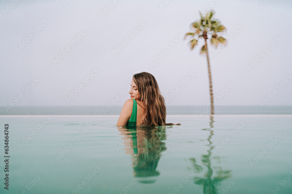 Chica delgada con pelo largo posando en una piscina de un hotel paradisiaco Chica delgada con pelo largo posando en una piscina de un hotel paradisiaco
