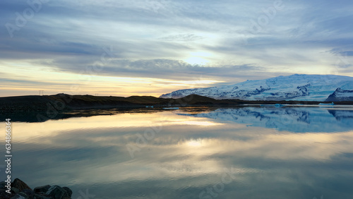 Lake and snowy mountains in iceland with beautiful landscape, freezing cold water. Scandinavian nature scenery with hills and fields, panoramic view scenic route. Handheld shot.