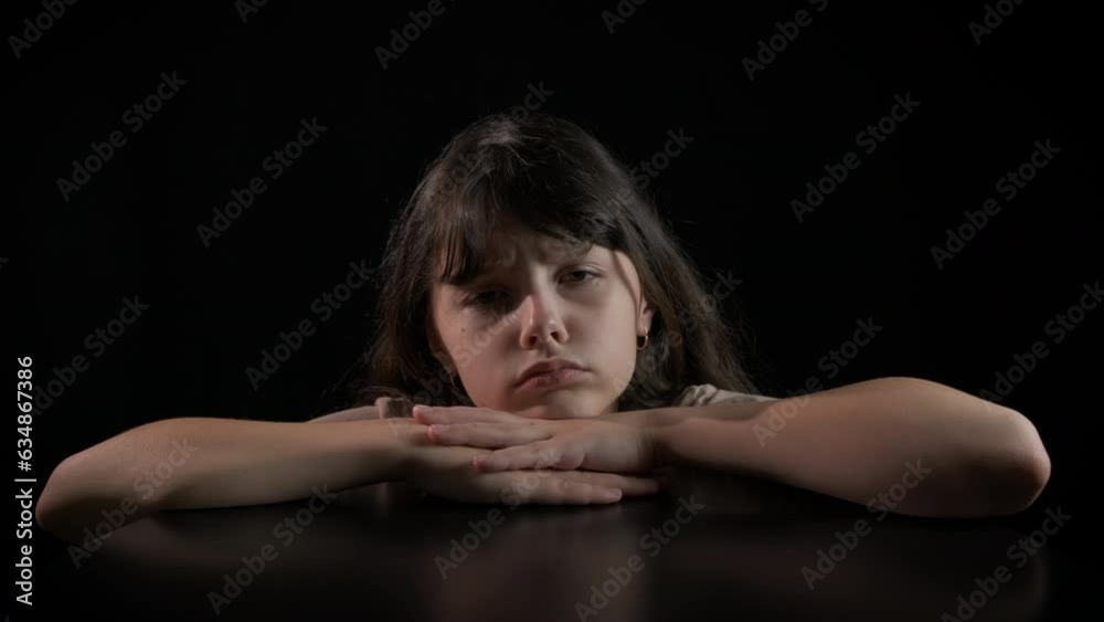 Stressed child against black background. A view of stressed little girl sitting in sadness against black background. Stressed child against black background. A view of stressed little girl sitting in sadness against black background.