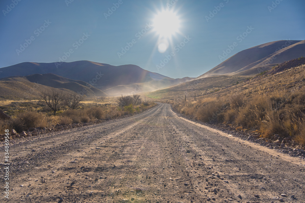 GRAVEL ROAD AT SUNSET. LONELY ROAD IN THE PUNA OF JUJUY. ARGENTINA.
