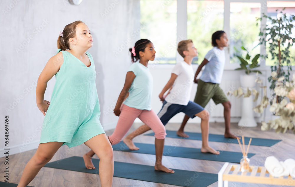 Fototapeta premium Active children doing stretching workout for body flexibility in yoga studio