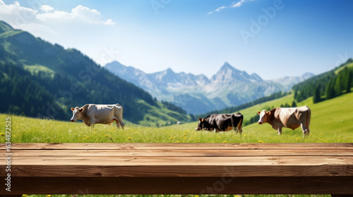 .Empty wooden tabletop for background and product montage, Adipian meadow with a herd of cows, natural dairy product banner and advertisement mockup with beautiful mountains alpine meadow behind