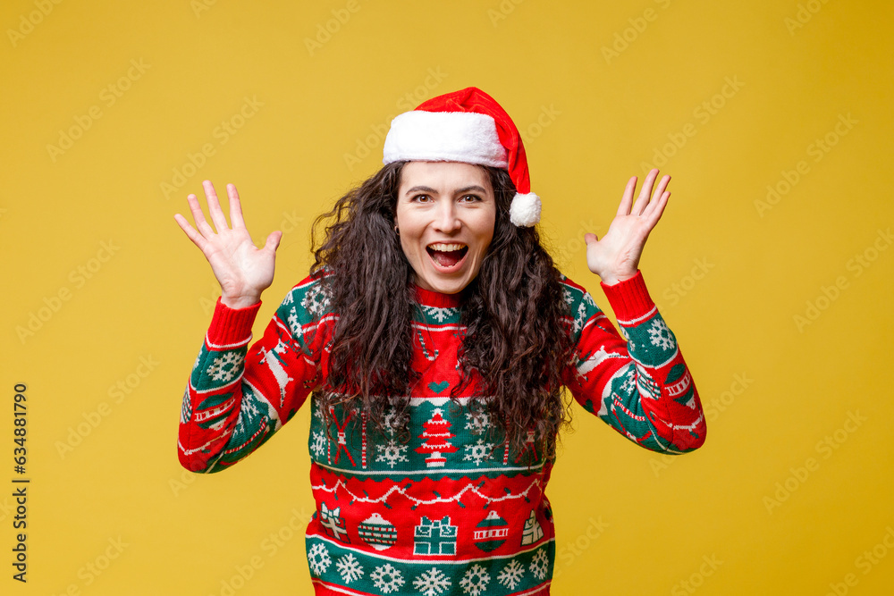 shocked girl in new year clothes and santa hat screams and panics on yellow isolated background