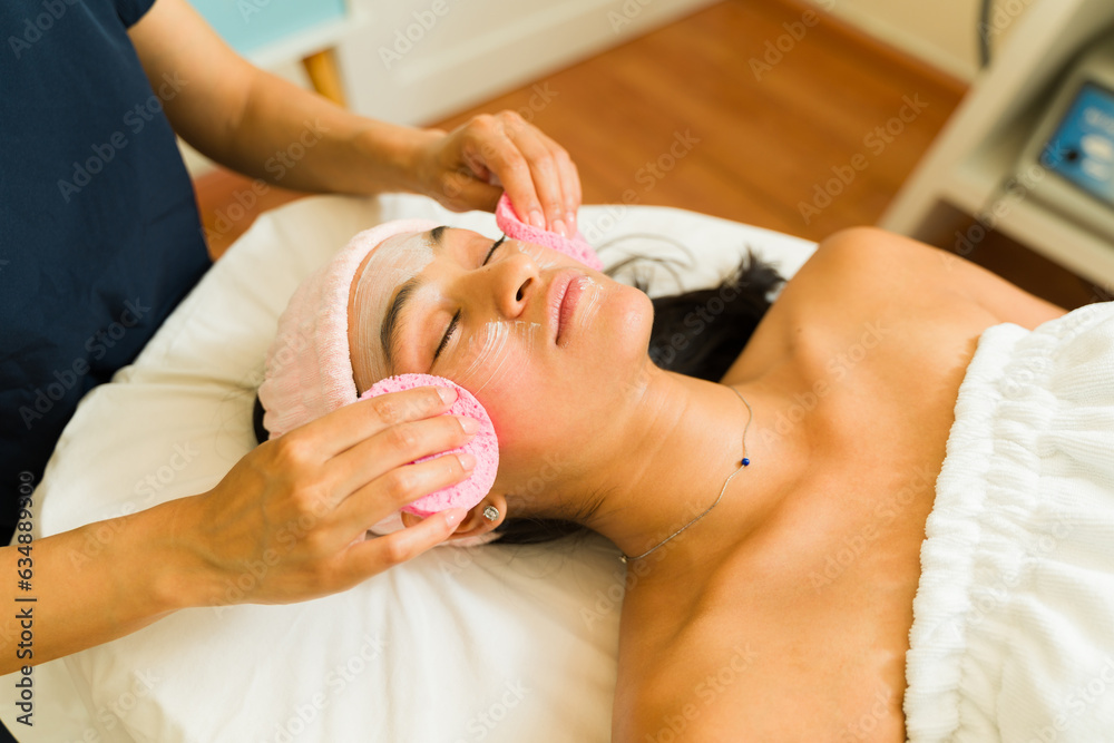 Young woman relaxing enjoying a facial treatment Young woman relaxing enjoying a facial treatment