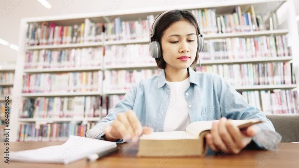 Asian female students university wear headphones Studying for Exams College Book in library Asian female students university wear headphones Studying for Exams College Book in library