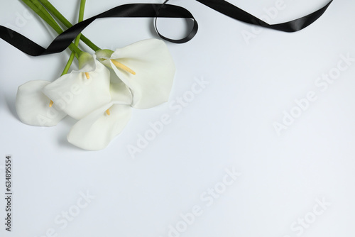 Fotobehang Beautiful calla lilies and black ribbon on white background, closeup with space for text
