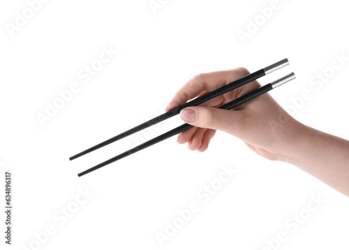 Woman holding pair of black chopsticks on white background, closeup