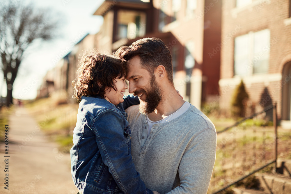 Father hugging his son while walking on a sidewalk in the suburbs of a city Father hugging his son while walking on a sidewalk in the suburbs of a city