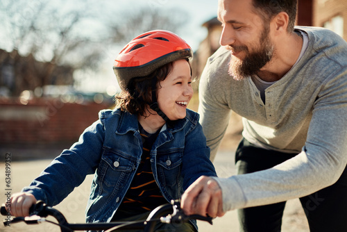 Father and son walking and riding a bike on the sidewalk in the city suburbs