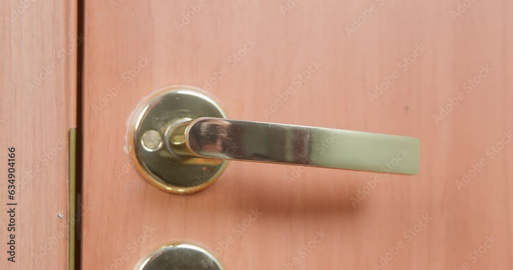 Close-up of golden doorknob on wooden door moving down up, trying to open, unlock. Modern interior , hotel room entrance, guests open, press handle. Apartment robbery, burglar alarm, metal fittings