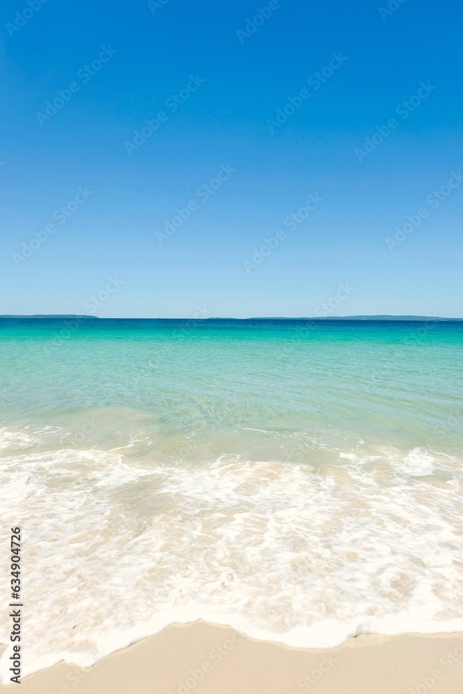 Clear turquoise waters, cloudless blue skies, and sea foam on a sunny day at Callala Beach in Shoalhaven — Jervis Bay National Park, New South Wales, Australia