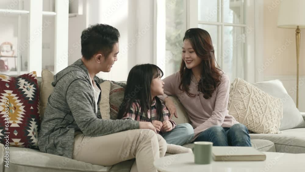 asian parents and daughter sitting on family couch having a pleasant conversation asian parents and daughter sitting on family couch having a pleasant conversation