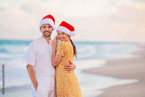 Portrait of Christmas happy couple in Santa hats on beach vacation having fun 