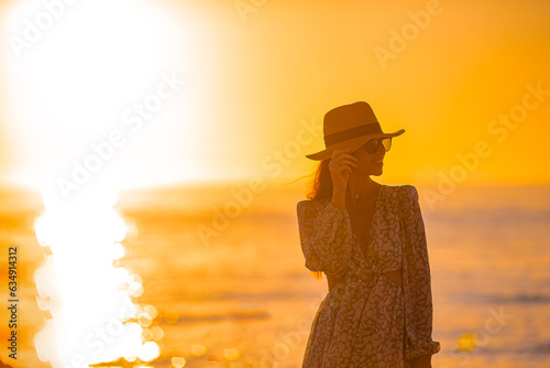 Young happy woman on the beach enjoy her summer vacation at sunset